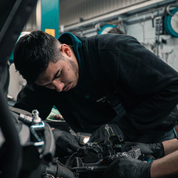 An automotive mechanic peers into the engine of a vehicle.